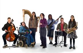 Members of the National Open Youth Orchestra pose in front of a white background with their instruments. One member of the group is a wheelchair user.